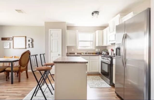 kitchen featuring white cabinets, a center island, light wood-type flooring, and stainless steel appliances