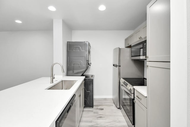 kitchen featuring stainless steel appliances, stacked washer / dryer, and sink