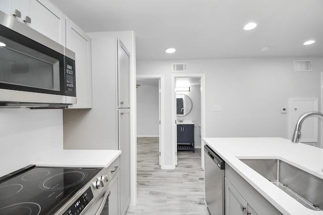 kitchen featuring white cabinets, stainless steel appliances, light hardwood / wood-style flooring, and sink