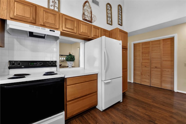 kitchen featuring decorative backsplash, a towering ceiling, white appliances, and dark hardwood / wood-style floors