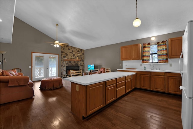 kitchen featuring kitchen peninsula, a stone fireplace, white fridge, and decorative light fixtures