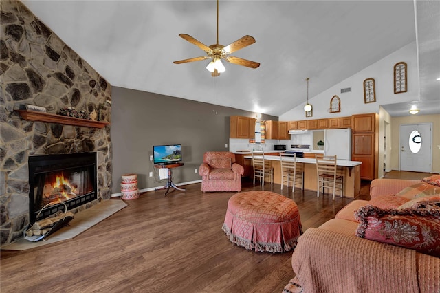 living room featuring dark hardwood / wood-style flooring, high vaulted ceiling, ceiling fan, and a stone fireplace