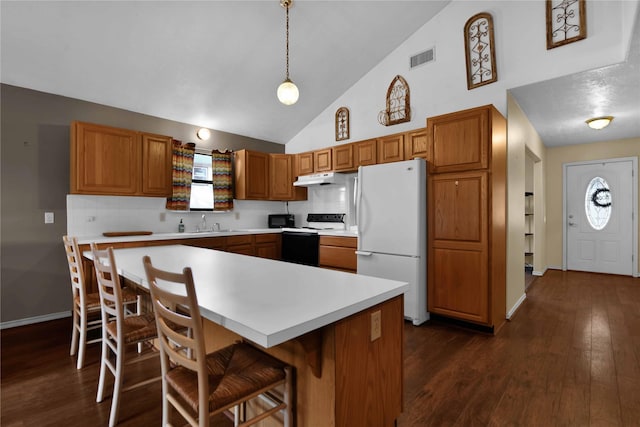 kitchen with pendant lighting, white appliances, a kitchen breakfast bar, dark hardwood / wood-style floors, and a kitchen island