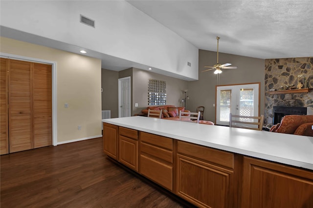 kitchen featuring high vaulted ceiling, french doors, a stone fireplace, dark hardwood / wood-style floors, and ceiling fan