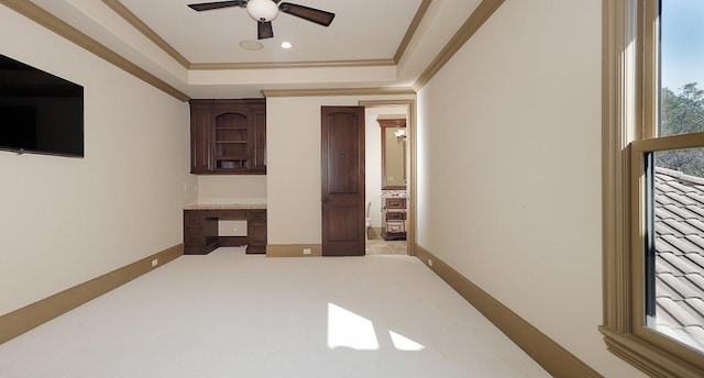 spare room featuring ceiling fan, built in desk, and ornamental molding