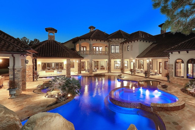 pool at dusk with an in ground hot tub and a patio