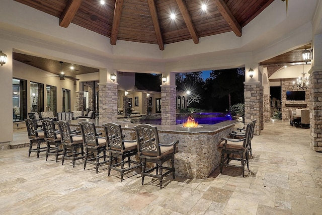 view of patio with exterior bar, an outdoor stone fireplace, and ceiling fan