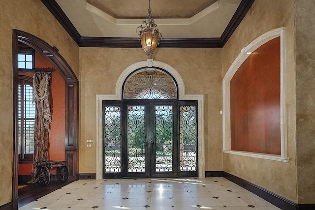 entrance foyer with crown molding, a tray ceiling, and french doors