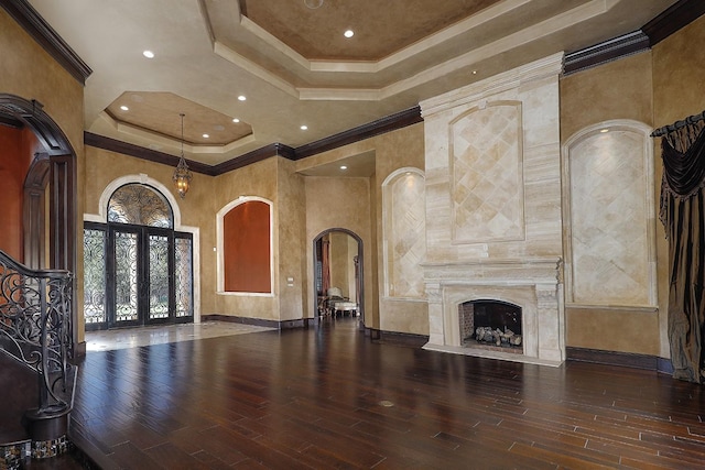 unfurnished living room with hardwood / wood-style floors, a raised ceiling, and crown molding