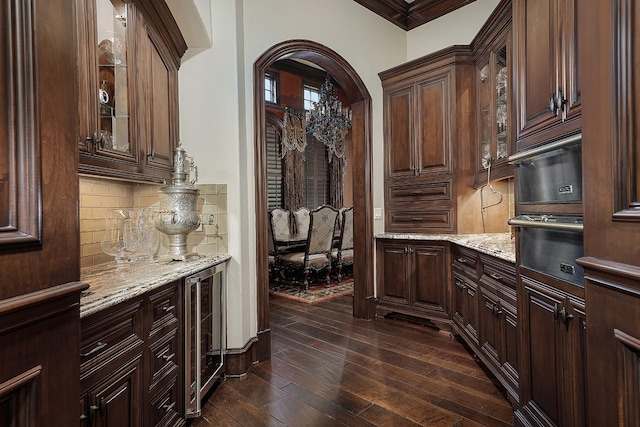 bar featuring dark brown cabinets, dark hardwood / wood-style flooring, ornamental molding, and backsplash