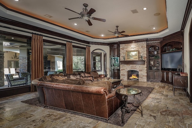 living room with decorative columns, ceiling fan, a fireplace, and crown molding