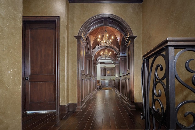 hallway with dark hardwood / wood-style floors, crown molding, and a notable chandelier