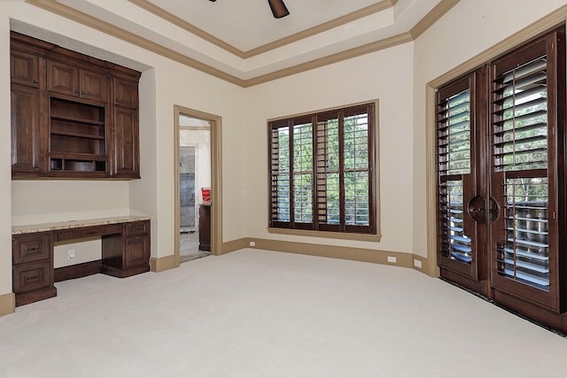 unfurnished office featuring light colored carpet, built in desk, ornamental molding, and a wealth of natural light