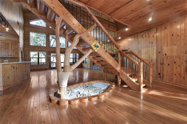 interior space featuring wood walls, wood-type flooring, wood ceiling, and a towering ceiling