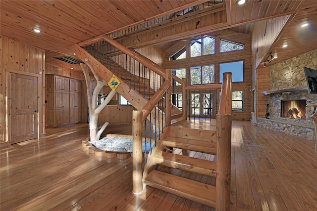 stairs featuring hardwood / wood-style flooring, plenty of natural light, and a stone fireplace