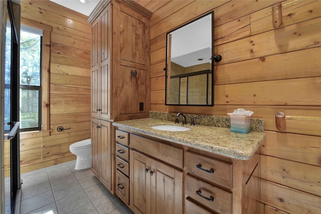 bathroom featuring tile patterned floors, vanity, toilet, and wooden walls