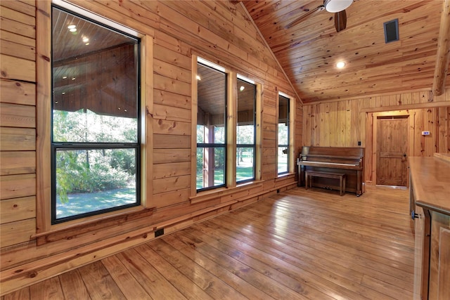 empty room featuring wooden walls, wood ceiling, vaulted ceiling, and light wood-type flooring