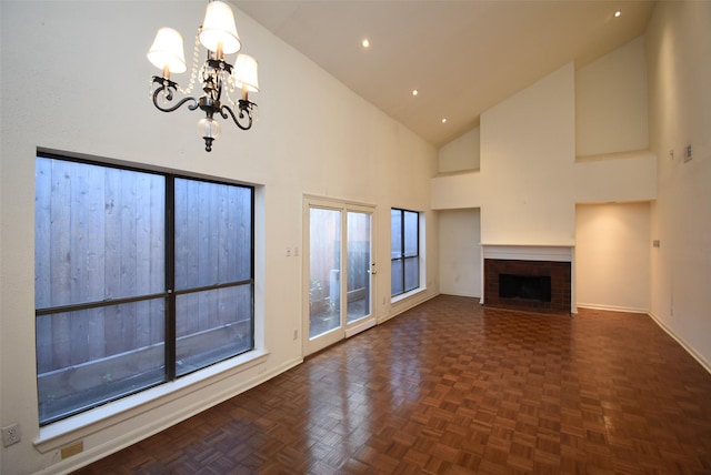 unfurnished living room featuring a brick fireplace, dark parquet floors, high vaulted ceiling, and a notable chandelier