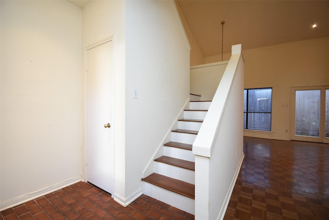 stairway with parquet flooring and a high ceiling