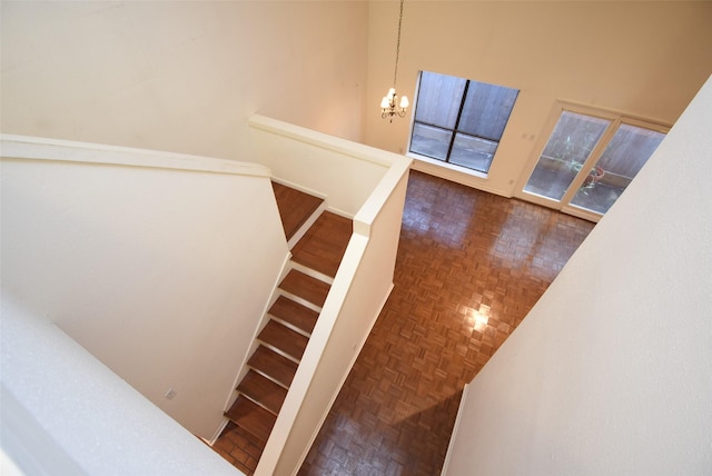 stairs featuring a notable chandelier, a high ceiling, and parquet flooring