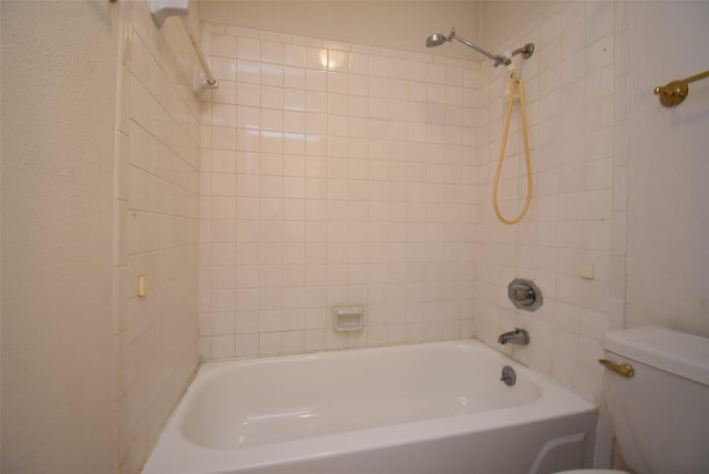 bathroom with tiled shower / bath combo and toilet