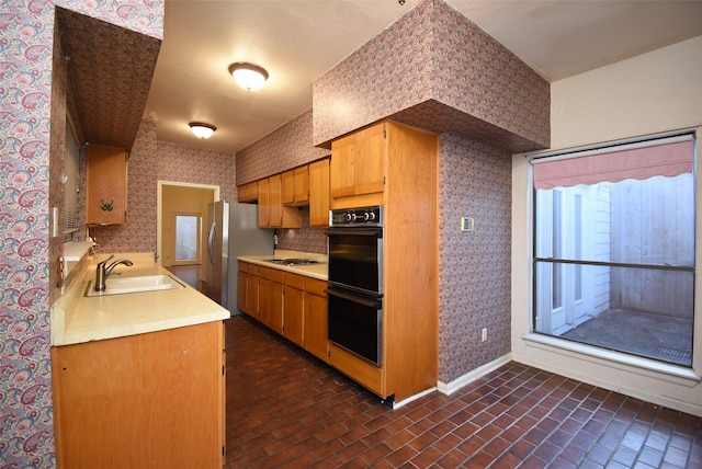 kitchen with stainless steel fridge, white gas stovetop, sink, and double oven