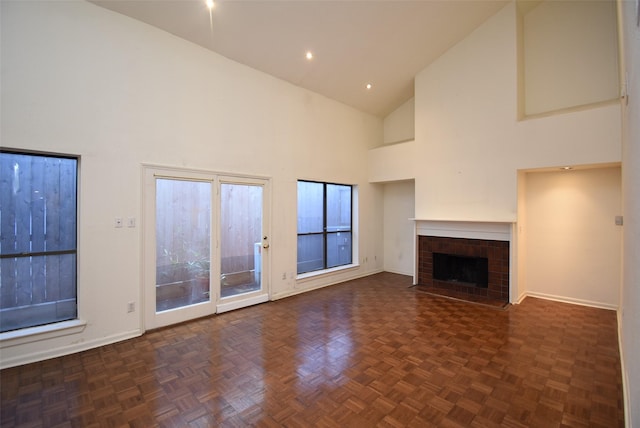 unfurnished living room featuring dark parquet flooring and high vaulted ceiling