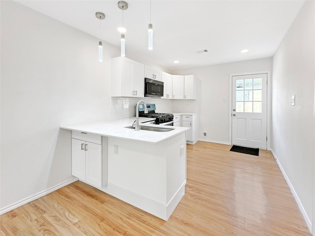 kitchen with stainless steel appliances, kitchen peninsula, pendant lighting, light hardwood / wood-style floors, and white cabinets