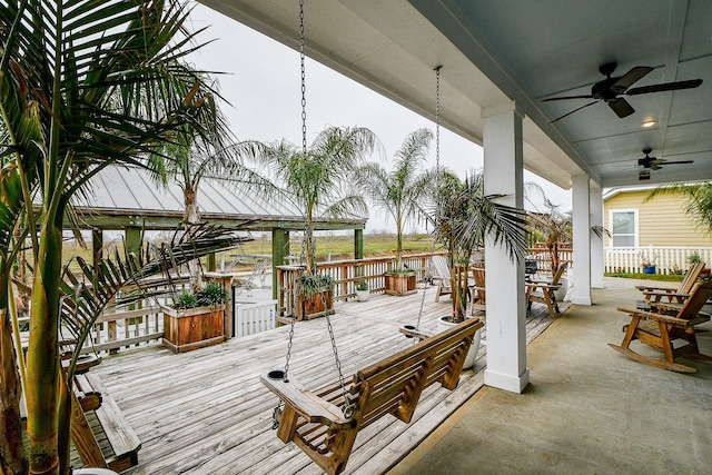 wooden terrace with covered porch, ceiling fan, and a water view