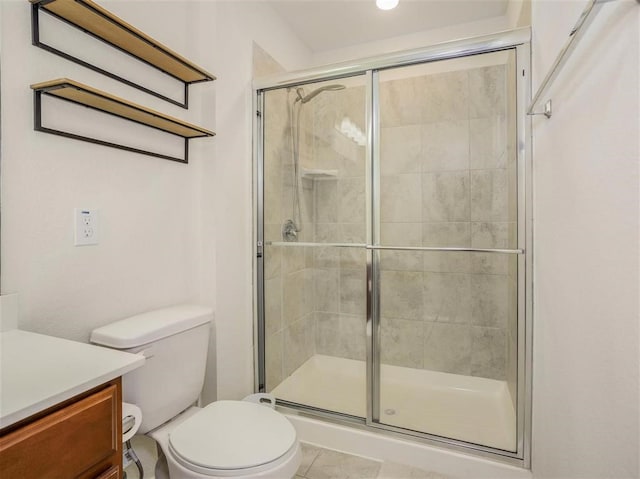 bathroom with tile patterned flooring, vanity, a shower with shower door, and toilet