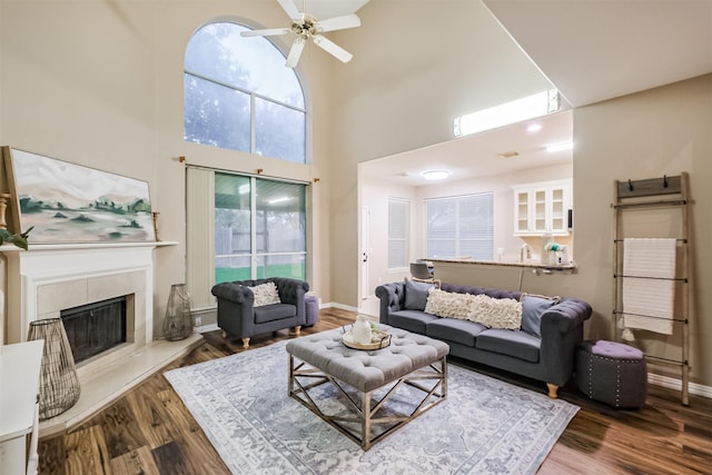3102 Silver Cedar Trl, Katy, TX 77449 - living area featuring a ceiling fan, a towering ceiling, wood finished floors, a tiled fireplace, and baseboards