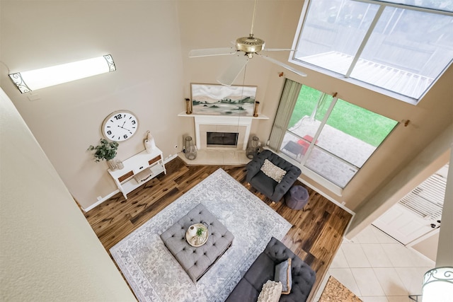 3102 Silver Cedar Trl, Katy, TX 77449 - living room with a ceiling fan, a tile fireplace, wood finished floors, a towering ceiling, and baseboards