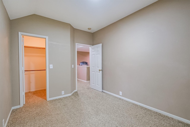 unfurnished bedroom with a spacious closet, a closet, and light carpet