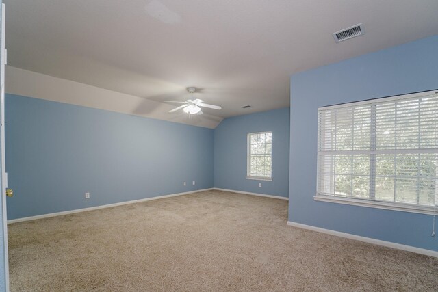 spare room featuring light carpet, vaulted ceiling, and ceiling fan