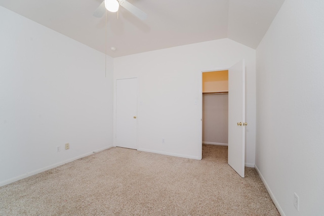 unfurnished bedroom featuring ceiling fan, vaulted ceiling, a walk in closet, light carpet, and a closet