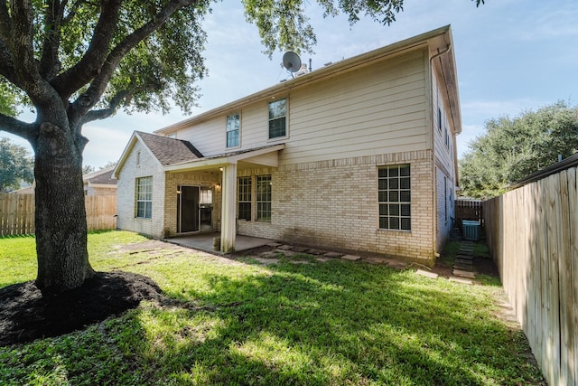 rear view of property with cooling unit, a patio area, and a yard