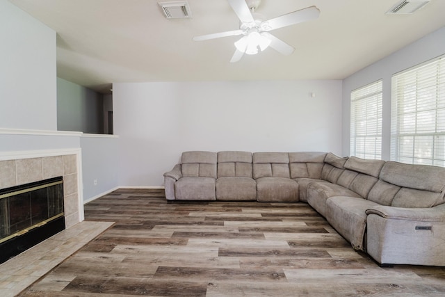 living room featuring ceiling fan, a fireplace, and hardwood / wood-style flooring