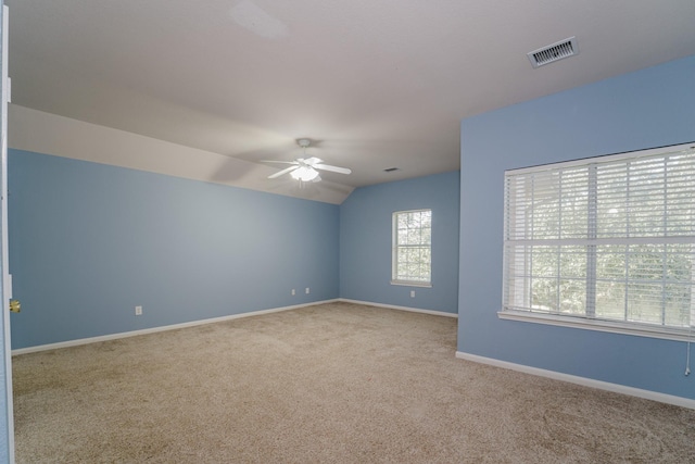 spare room featuring light colored carpet, vaulted ceiling, and ceiling fan