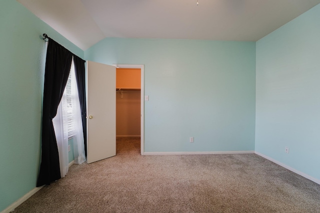 carpeted spare room with lofted ceiling