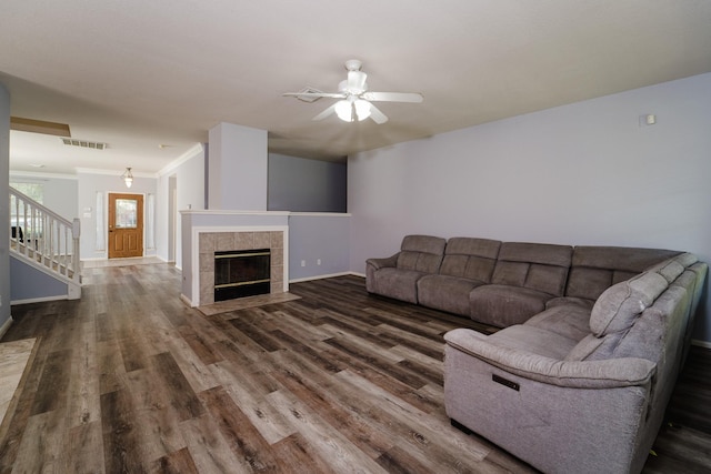 living room with a fireplace, dark hardwood / wood-style floors, ceiling fan, and ornamental molding