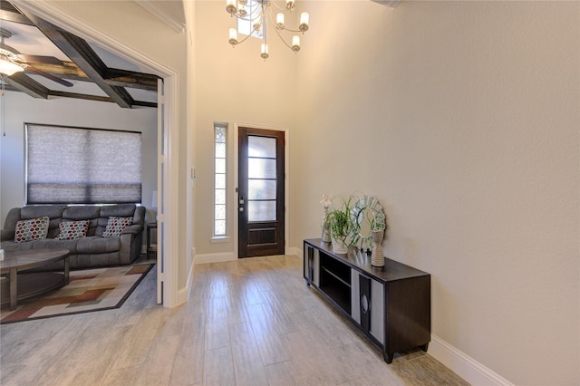 foyer entrance featuring ceiling fan with notable chandelier, beam ceiling, and light wood-type flooring