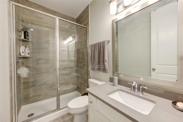 bathroom featuring a shower with door, vanity, and toilet