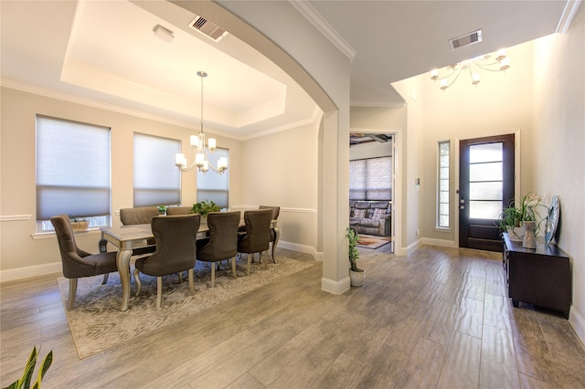 dining area with hardwood / wood-style floors, crown molding, a tray ceiling, and an inviting chandelier