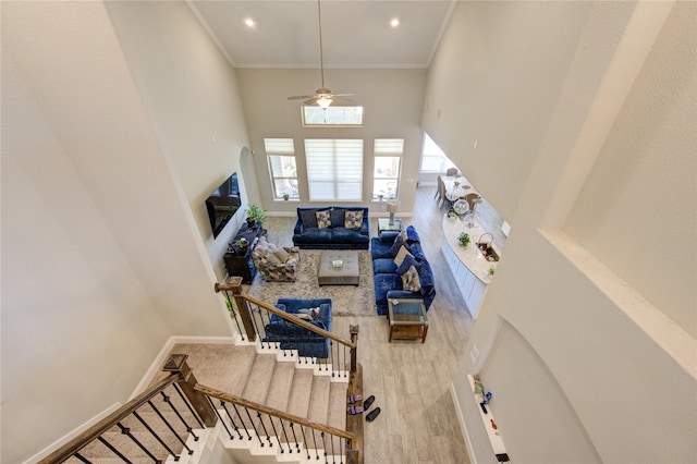 living room with ceiling fan, crown molding, a towering ceiling, and hardwood / wood-style flooring