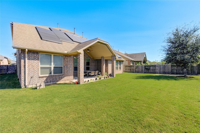 rear view of house featuring solar panels, a patio area, and a lawn