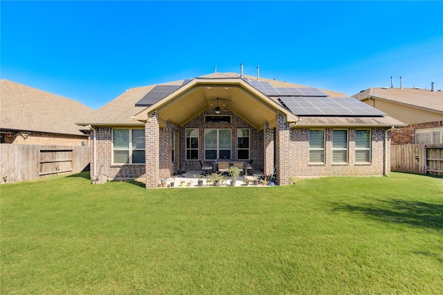 rear view of house featuring solar panels, a patio area, and a lawn