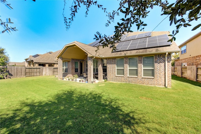 rear view of house featuring solar panels and a yard