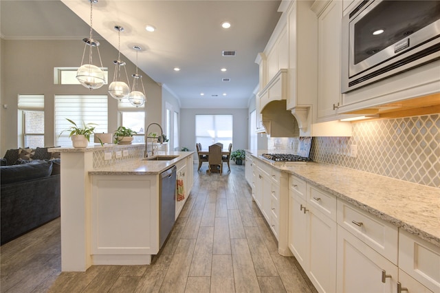 kitchen featuring white cabinetry, sink, stainless steel appliances, light hardwood / wood-style flooring, and pendant lighting