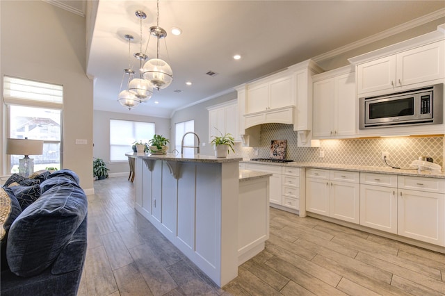 kitchen featuring hanging light fixtures, light stone countertops, light hardwood / wood-style floors, white cabinetry, and stainless steel appliances