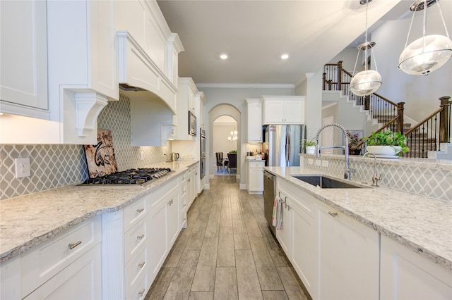 kitchen featuring light stone countertops, appliances with stainless steel finishes, white cabinetry, and pendant lighting